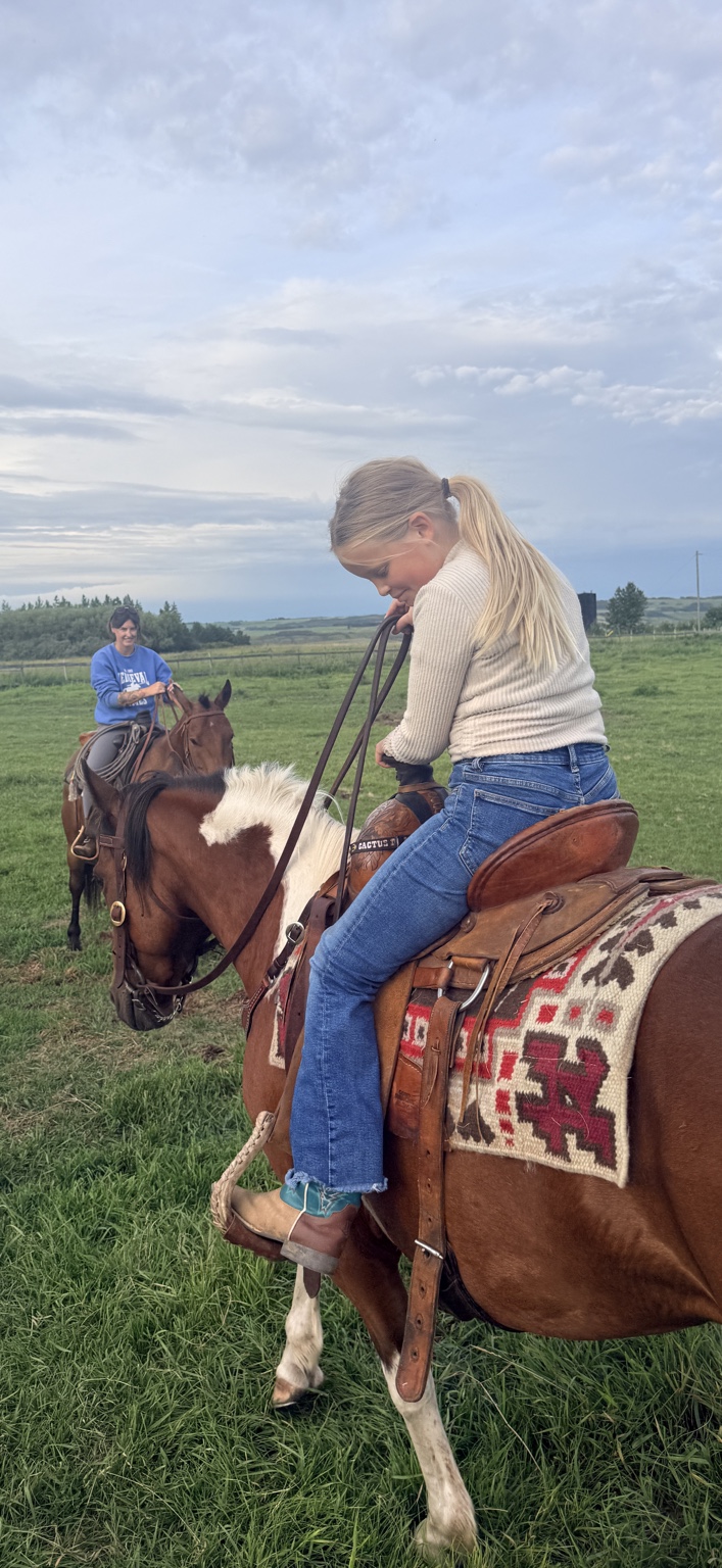 Ellie riding a horse on the ranch
